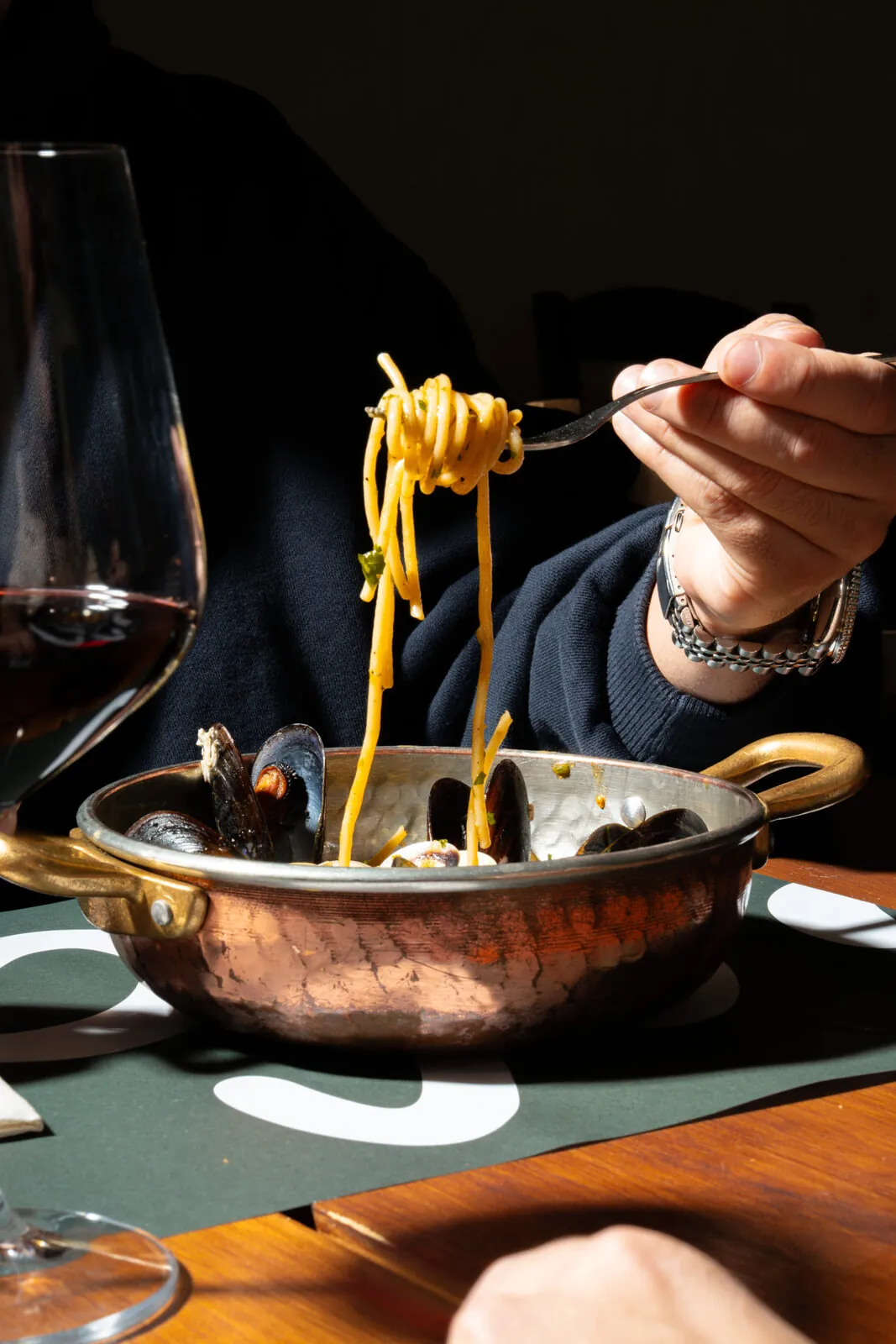 Spaghetti alle vongole servidos en cazuela de cobre con copa de vino — sesión editorial A'Napule
