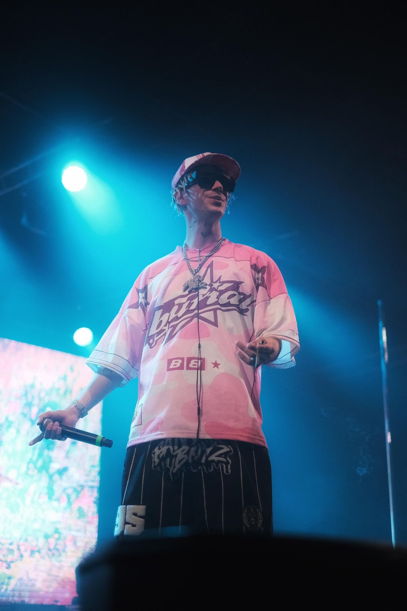 Kidd Keo cantando sobre el escenario con luces rojas