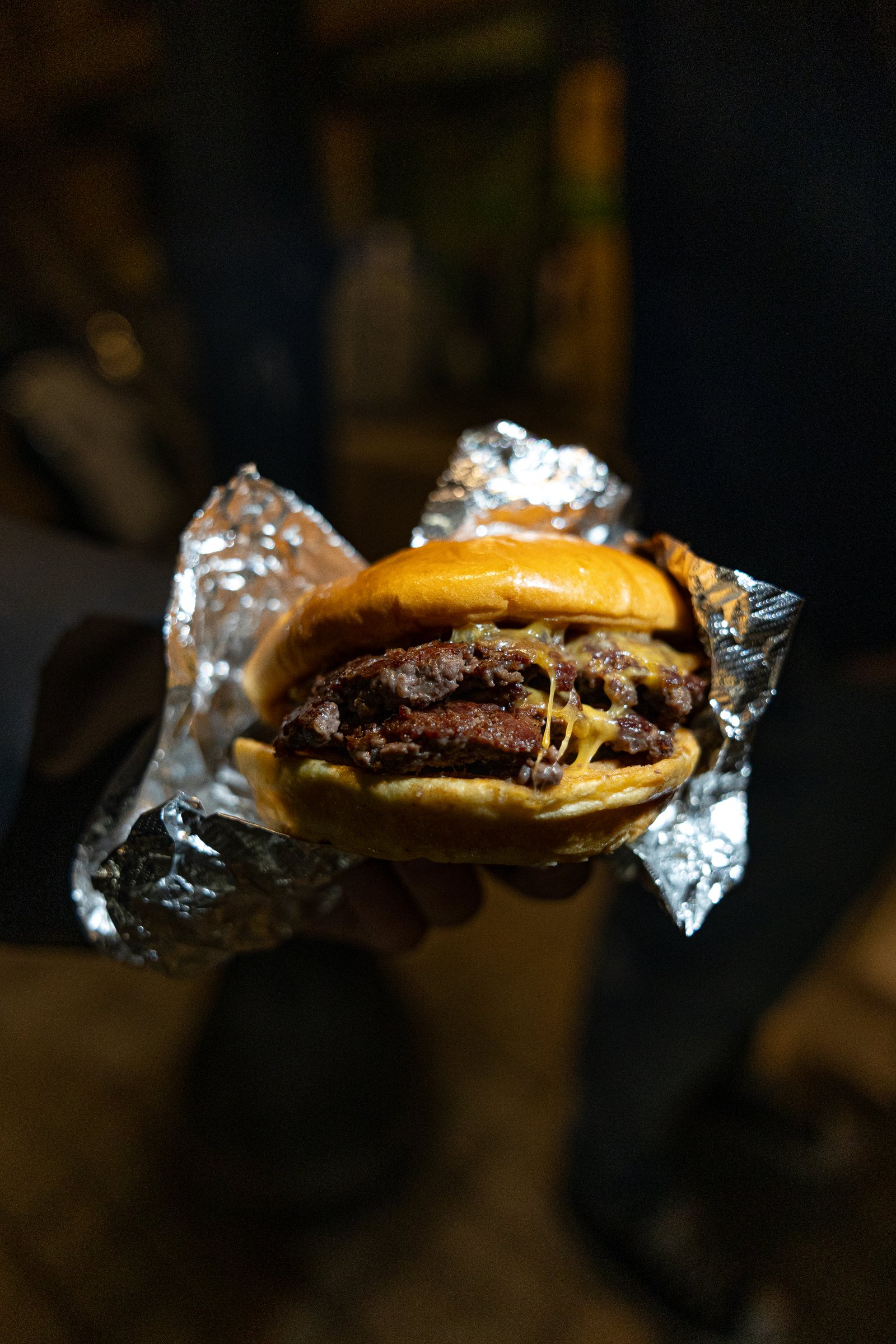 Smash burger envuelta en papel de aluminio, fotografía nocturna en la calle